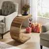 A C-shaped side table with a cup of coffee and a vase of flowers on top, next to a tufted armchair. Christmas stockings and gifts are placed on the floor beside the table. Anteprima dell’immagine prodotto