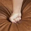 A close-up shot of a fist pressing into a brown, textured surface, likely upholstery. Produktbild-Vorschau
