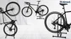 A collage of three images showing a black bicycle on a black bicycle stand, with a logo and text in the top right corner. Náhľad obrázku produktu