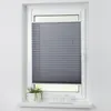 A grey pleated blind is installed in a white window frame. A small potted plant and three white glasses are on the windowsill below. Produktbild-Vorschau