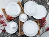 A collection of white ceramic plates and cups arranged on wooden trays and a chalkboard-style background with decorative red berries. Náhľad obrázku produktu