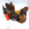 A brown inflatable horse toy with an orange ribbon and red mane, lying on its side next to an orange and black hand pump. Instructional diagrams and text are visible on a white surface below the toy. Produktbild-Vorschau