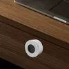 A close-up shot of a small, round fingerprint lock with a marble-like pattern on a wooden surface, next to a laptop. Podgląd zdjęcia produktu