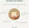 A hand holding a bar of soap with text annotations describing its natural formula. Produktbild-Vorschau