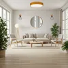 A modern living room with a sofa, chairs, coffee table, and plants, illuminated by a ceiling lamp. Produktbild-Vorschau