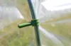 A close-up of a green plastic clip attached to a green pole, with a clear plastic sheet in the background. Náhled obrázku produktu