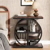 A bedside table with a lamp, books, and a camera, next to a bed. Anteprima dell’immagine prodotto