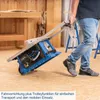 A person is pulling a blue table saw on a trolley function across a wooden floor in a workshop. Produktbild-Vorschau