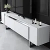 A white TV stand with silver legs is shown in a modern living room setting. Voir les images du produit