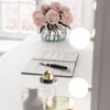 A vanity table setup with a notebook, pen, flowers, and perfume bottles. Produktbild-Vorschau