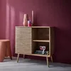 A wooden sideboard with a slatted sliding door, decorated with vases and candles, next to a pink stool, against a deep pink wall. Anteprima dell’immagine prodotto
