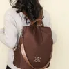 Brauner Rucksack mit goldfarbenem ineinandergreifendem Logo, auf dem Rücken einer Person in einem hellgrauen Pullover getragen Anteprima dell’immagine prodotto