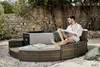 A man is relaxing on a circular outdoor sofa next to a whirlpool. Produktbild-Vorschau