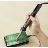 A hand holding a desoldering tool over a circuit board. Produktbild-Vorschau