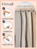 A collage of product details for wooden hangers with clips, showing close-ups of the material, hook, and clips, next to a row of trousers hanging on the hangers. Produktbild-Vorschau