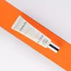 A cosmetic product tube is placed on an orange surface against a white background. Náhled obrázku produktu