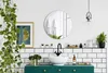 A modern bathroom with a round mirror, sink, and green vanity, decorated with plants. Produktbild-Vorschau
