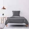 A bed with gray bedding and a pillow in a minimalist room. Produktbild-Vorschau