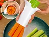 A person is using a vegetable slicer to cut carrots and cucumbers into strips, with the cut vegetables falling into a bowl. Podgląd zdjęcia produktu