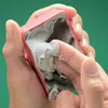 A close-up shot of hands interacting with a modeling paste product in a pink container. Podgląd zdjęcia produktu