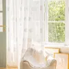 A sheer curtain with cloud patterns hangs in front of a window, with a chair and framed pictures visible. Produktbild-Vorschau