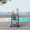 A dark gray outdoor serving cart is placed on a wooden deck next to a swimming pool with islands in the background. Anteprima dell’immagine prodotto