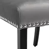 A close-up view of the side of a gray upholstered chair with silver nailhead trim and black legs. Produktbild-Vorschau