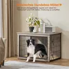 A dog is inside a wooden dog crate that doubles as a piece of furniture, with a plant and speaker on top. Produktbild-Vorschau