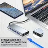 A laptop, smartphone, and docking station are arranged on a wooden surface, with a network cable in the foreground. Produktbild-Vorschau