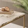 A close-up of a marble-top coffee table with books and a candle. Náhled obrázku produktu