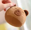 A hand is holding a small, round, brown plush toy that resembles a bear. Anteprima dell’immagine prodotto