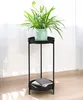 A plant stand with a plant on top and books on the bottom shelf, placed indoors. Podgląd zdjęcia produktu