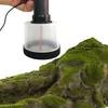 A hand holding a mini flocking machine over a model landscape with mossy rocks. Náhled obrázku produktu