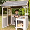 A young child is playing in a wooden playhouse with a play kitchen. Anteprima dell’immagine prodotto