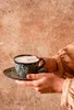 A person holding a cup of coffee on a saucer. Podgląd zdjęcia produktu