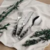 A set of cutlery laid out on a textured cloth with greenery. Anteprima dell’immagine prodotto