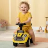 A baby is happily riding a yellow toy car indoors. Produktbild-Vorschau