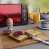 A breakfast scene with a red toaster, toast, jam, egg, orange juice, and coffee. Produktbild-Vorschau