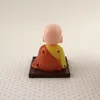 A small figurine of a meditating Buddha sits on a wooden base, viewed from the back. Produktbild-Vorschau