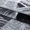 A close-up view of a folded carpet with an abstract pattern in shades of gray, black, and white. Náhled obrázku produktu