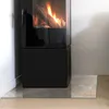A glass hearth plate in front of a modern black fireplace with a fire burning inside. Produktbild-Vorschau