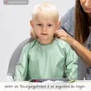 A child wearing a bib is being helped by an adult. Produktbild-Vorschau