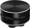 A black, circular Bluetooth speaker with silver trim and buttons on its side, resting on a white surface. Náhľad obrázku produktu