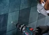 A person is drilling a hole in a tiled wall. Podgląd zdjęcia produktu