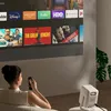A woman is using a projector in a living room setting. Produktbild-Vorschau