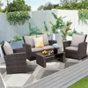 A patio furniture set is arranged on a rug on a wooden deck, with plants and a white fence in the background. Produktbild-Vorschau