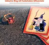 A ring and cards with a witch illustration are placed on a dark, sandy surface. Produktbild-Vorschau
