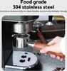 A hand holding a portafilter with a wooden handle, attached to an espresso machine. Coffee beans are scattered on the counter. Anteprima dell’immagine prodotto