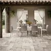 An outdoor dining set with chairs and a table on a stone patio, under a tiled roof. Produktbild-Vorschau