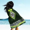 A person on a beach wearing a blanket with a football stadium design. Produktbild-Vorschau